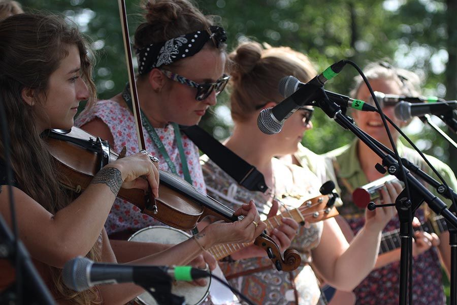 a group of fiddlers play on an outdoor stage on a summer day 