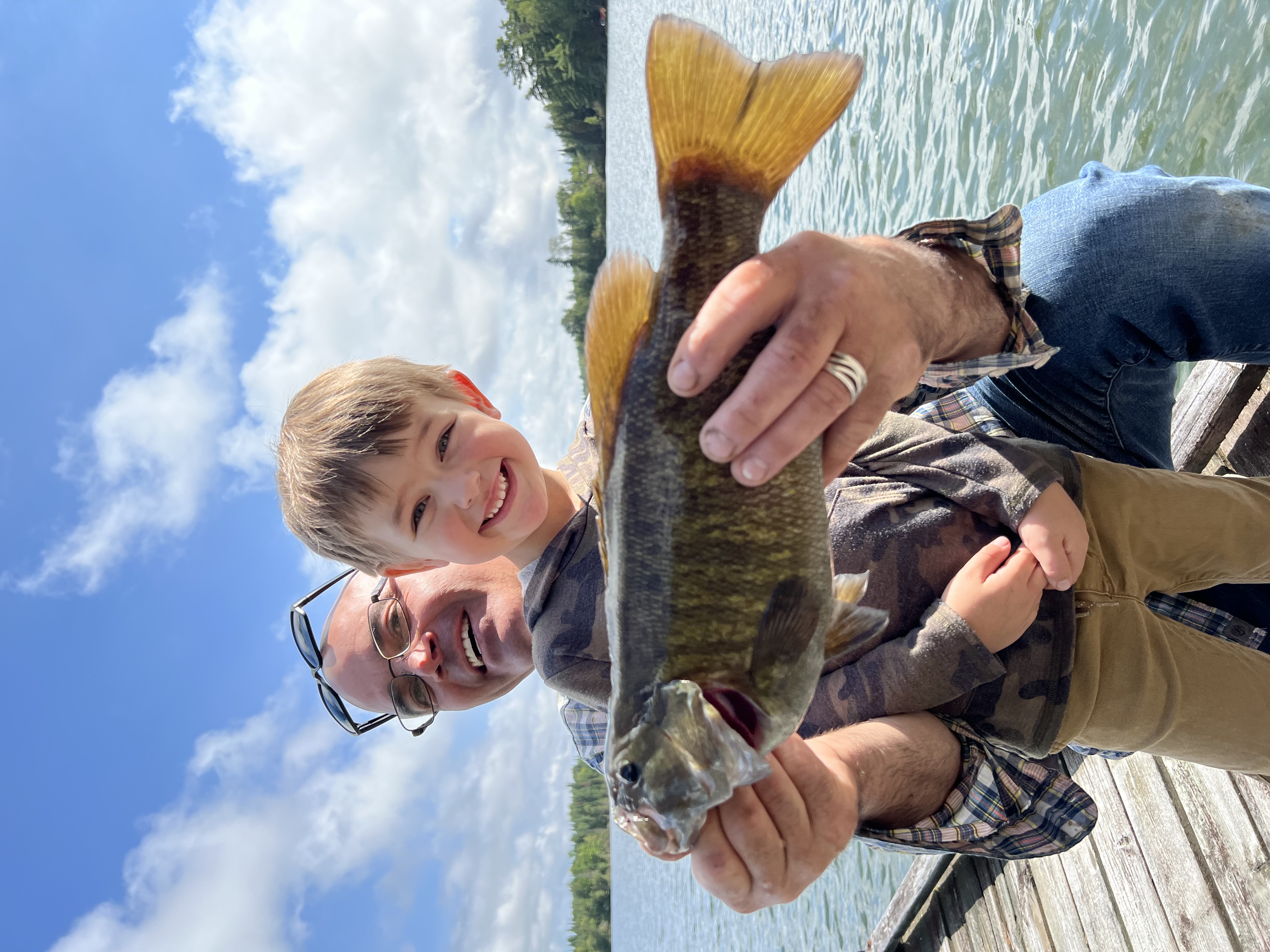 A father and son hold up a freshly caught fish