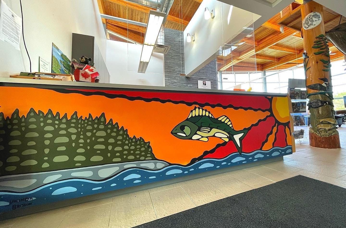 a brightly colorful mural of a fish, sunset, lake, and forest dominate the entrance welcome area.